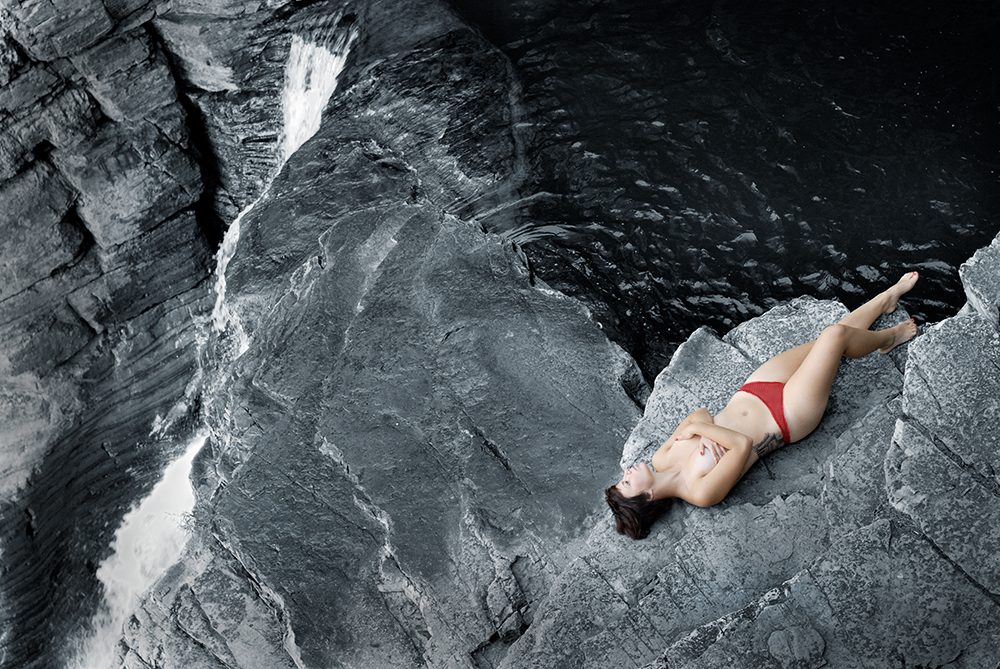 Photographie d'une femme semi-nue dans un décor naturel de rochers / nu féminin et cascade d'eau